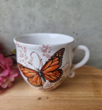 Tekopp med oransje sommerfugl